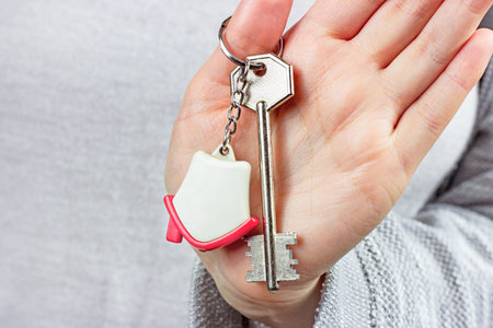 Caucasian woman hands holding the keychain with the keys and small house key ring close up....
