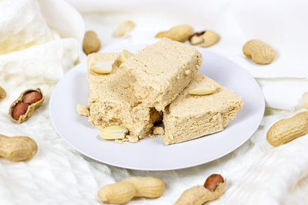 Traditional sweet turkish delight halva pieces with peanut nuts on light background.