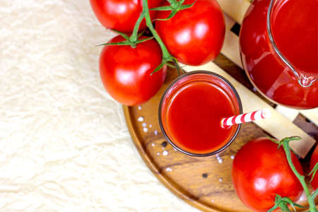 Top view of fresh homemade tomato juice in a glass and a jug on wooden background with copy space.の写真素材