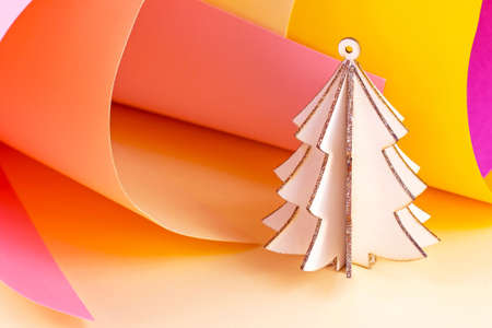 Bright wooden pink Christmas tree on colorful magenta and yellow paper swirls abstract background with copy space. Simple New Year and Xmas holidays template for greeting cards and winter decorations.の写真素材
