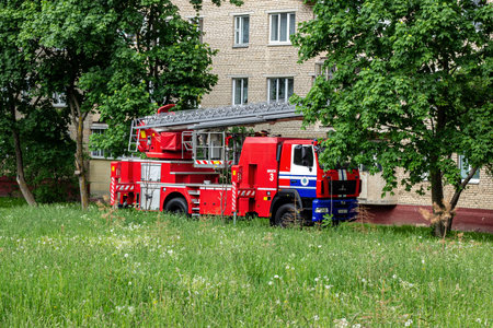 MINSK, BELARUS - MAY 26, 2019: Big red fire engine car with firefighters and emergency ladder near...