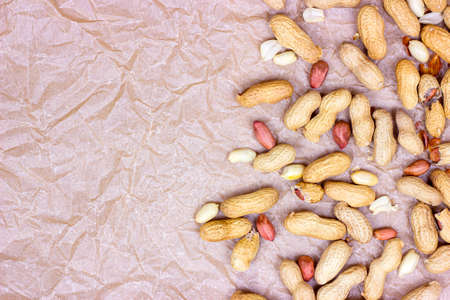 Top view of raw unpeeled peanut nuts in nutshell on light paper background with copy space.の写真素材