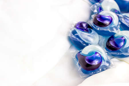 Bright blue washing pods and capsules with liquid detergent for machine laundry on white clothing background with copy space.の写真素材