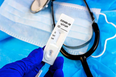 Medical covid-19 antibody and antigen rapid self test in doctor hand in blue gloves on light blue background.の写真素材