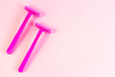 Pink disposable woman razor on light pastel background with copy space top view. Hair removing, epilation procedure and shaving concept.の写真素材