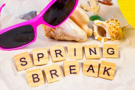 Words Spring Break on yellow sandy textured background with bright sunglasses, seashells and stones. Students sea holiday tourism and tropical vacations concept.の写真素材