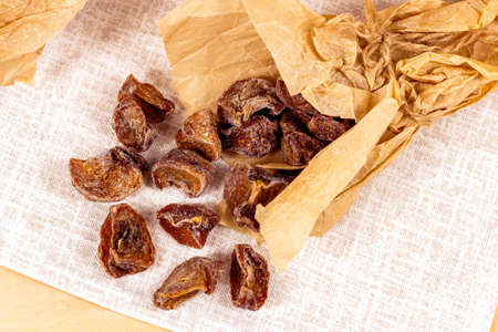 Traditional Japanese hoshigaki dried persimmon fruit snack slices in wrapping paper on light background top view.の写真素材