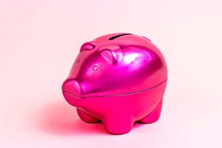 Bright pink piggy bank for coins on light rose background.