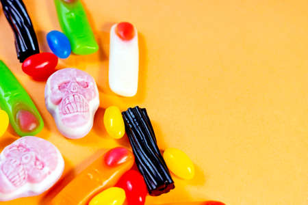 Different spooky Halloween jelly sweets (skulls, zombie fingers and beans) as a frame on orange background with copy space.の写真素材