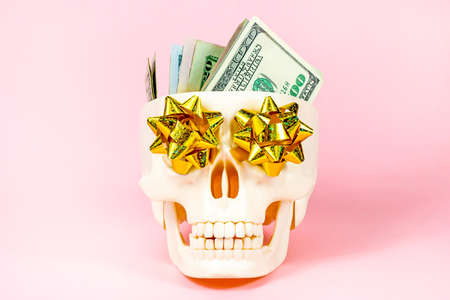 Human skull with American dollars on light pink background. Money, lottery win, legacy concept.の写真素材