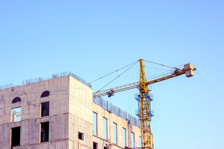 High crane for house building at the construction site on blue sky background.