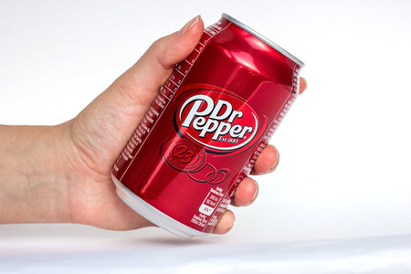 DUSHANBE, TAJIKISTAN - SEPTEMBER 11, 2022: Woman hands holding the red aluminium Dr. Pepper can close up on white background.のeditorial素材