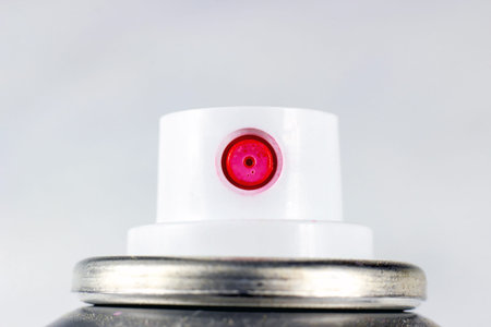 Pink acrylic spray paint white plastic cap on a metal can close up on light background with copy...