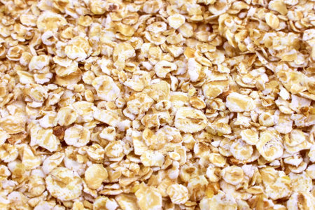 Yellow oats flakes breakfast cereal texture close up.