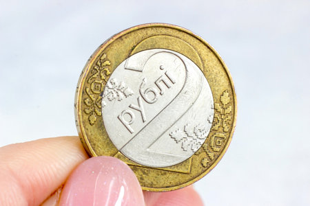 Woman hands holding Belarusian two rubles coin on light background close up.の写真素材