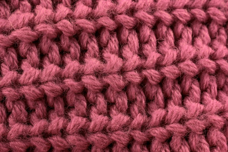 Pink color knitted textured handmade fabric as a textile background close up.