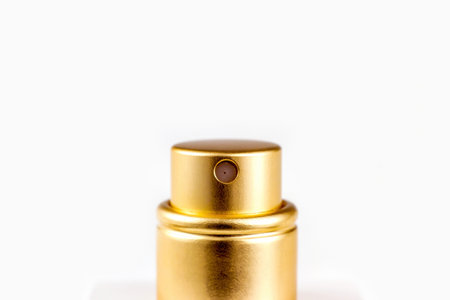 Golden perfume spray cap on light background close up with copy space.の写真素材