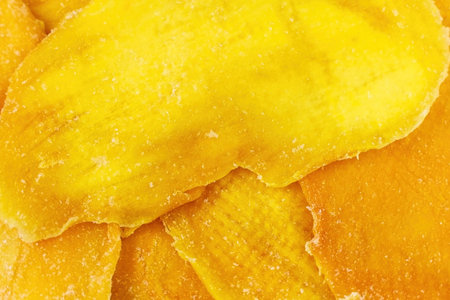 Bright yellow dried mango slices texture close up top viewの写真素材