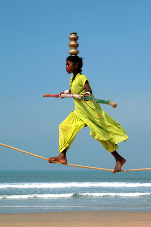 GOA, INDIA - FEB 12  Wandering indian tightrope walker playing on the beach of Goa, on Feb 12, 2008  Small groups of buskers traveling along the coast and often arrange free shows for tourists on the beachのeditorial素材