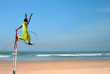 GOA, INDIA - FEB 12  Wandering indian tightrope walker playing on the beach of Goa, on Feb 12, 2008  Small groups of buskers traveling along the coast and often arrange free shows for tourists on the beachのeditorial素材