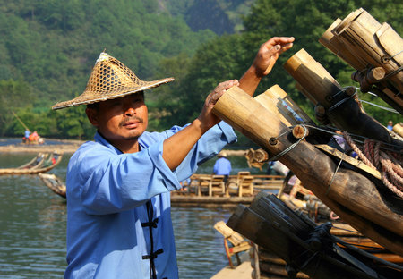 WUYISHAN, FUJIAN, CHINA - OCT 20, 2009: Chinese man preparing bamboo rafts to travel on the River of Nine Bends. Bamboo rafting is very popular tourist attraction in the scenic area of Wuyi mountainsのeditorial素材