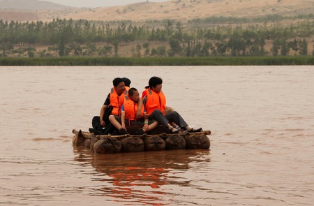 NINGXIA, CHINA - JUL 9, 2011: Tourists floating along the Yellow River (Huang He) on a sheepskin rafts. Balloons of these exotic rafts really made of sheep skin by locals. Shapotou Tourism areaのeditorial素材