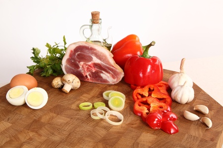 Piece of pork, vegetables, eggs and oil on a chopping boardの写真素材