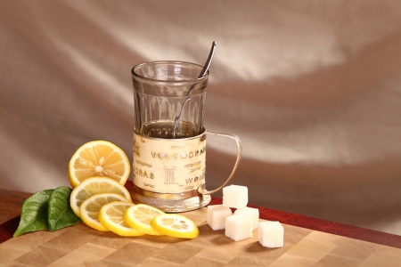 Black tea in a glass mug, a lemon and refined sugar on a wooden boardの写真素材