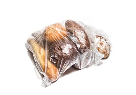 Different kinds of bread in transparent plastic bag isolated on whiteの写真素材