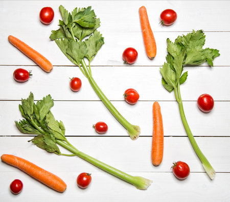 Fresh vegetables on white wooden table. Top view. Celery, carrot and tomatoes patternの写真素材