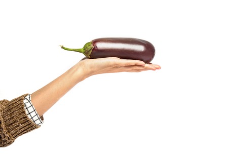Woman's hand holds eggplant isolated on white backgroundの写真素材