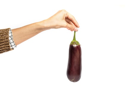 Woman's hand holds eggplant isolated on white backgroundの写真素材