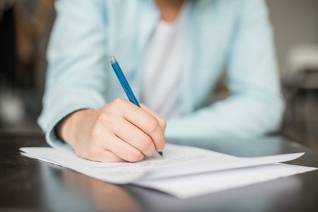 Man writing at the desk. Hands with piece of paper or document and pen. Signing the contract