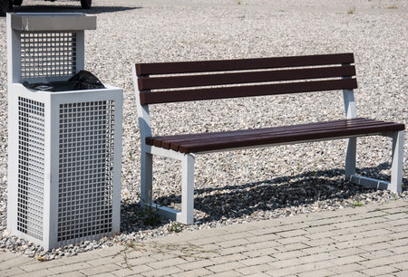 a modern bench and trash can on gravel sidewalkの写真素材