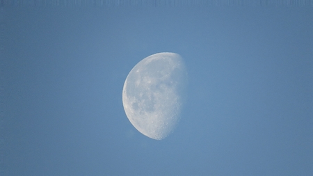 Beautiful Moon visible during a day on a cloudy skyの写真素材