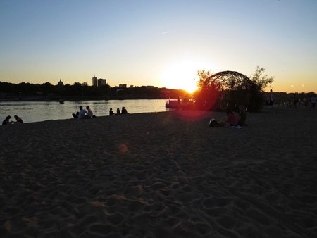 People Enjoying Evening at a Beach with a Beautiful City Skyline Panorama in Background Seen During Sunsetの写真素材