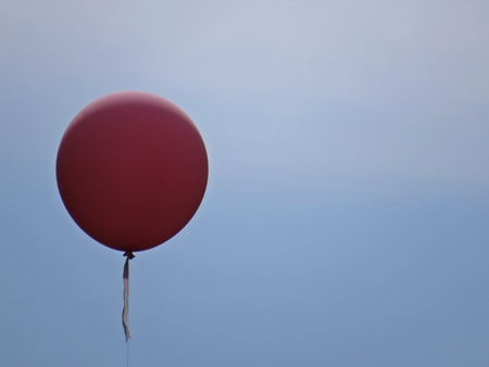 Isolated Pink Helium Balloon Flying with a Blue Sky and White Clouds in the Backgroundの写真素材