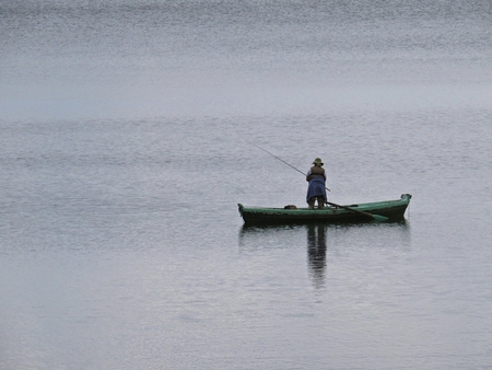 Fisherman on Fishing Boat with Calm Water Surface in the Backgroundの写真素材
