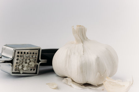 Garlic press and garlic on a white background. Selective focus.の写真素材