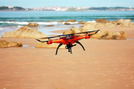 Flying quadrocopter with mounted camera on the beachの写真素材