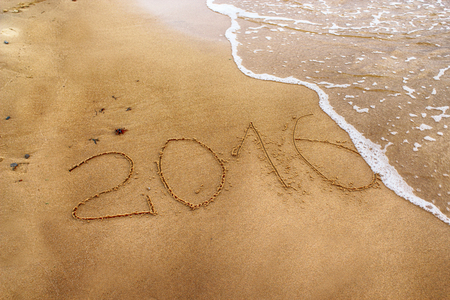 2016 year drawing on the sand washed away by the waveの写真素材