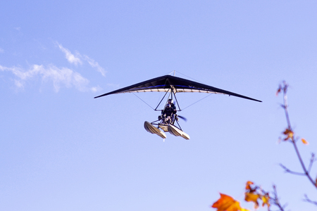 Motorized hang glider flying in the blue  cloudy sky in autumn timeの写真素材