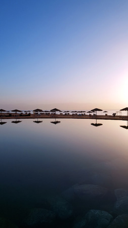 Sunset in a swimming pool. Silhouette of umbrellas on the beach in Egypt. Reflection on the waterの写真素材
