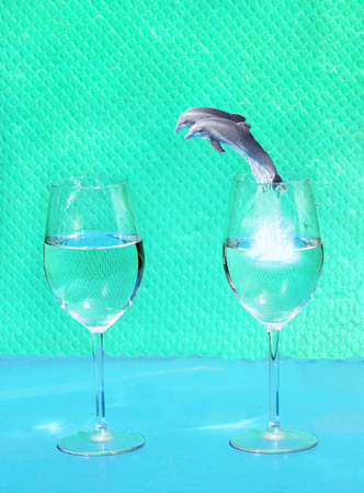 Two dolphins jumping from one glass of water into anotherの写真素材