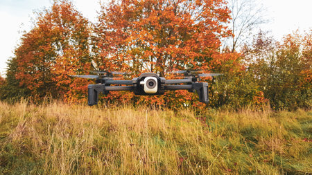 Flying drone with mounted camera in autumn park. Technology and military concept