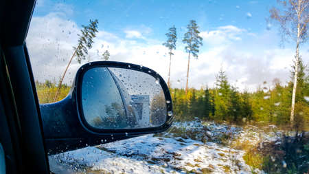 Car caravaning travel trip active vacation on sunny winter day, indoor view from car to front side window to outdoor back view mirror caravan trailer reflection. Caravanning, car traveling and winter holidays concept.の写真素材