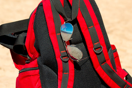 Red backpack and sunglasses on the beach, closeup. Sport and recreation conceptの写真素材