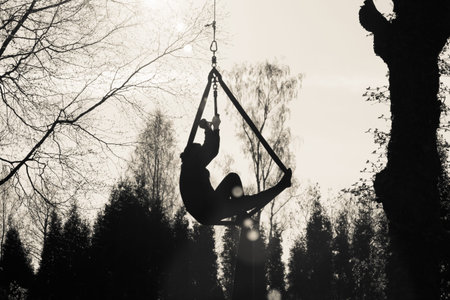 Sport exercises with aerial silk outdoor - in the park or in the yard