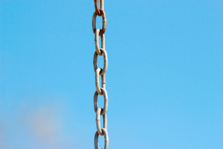 Metal chain from a swing in park on a background of blue day sky