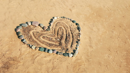 The heart shape is made from various stones on the sand in the beach. Love, marriage,  honeymoon,  and Valentine Day concept.の写真素材